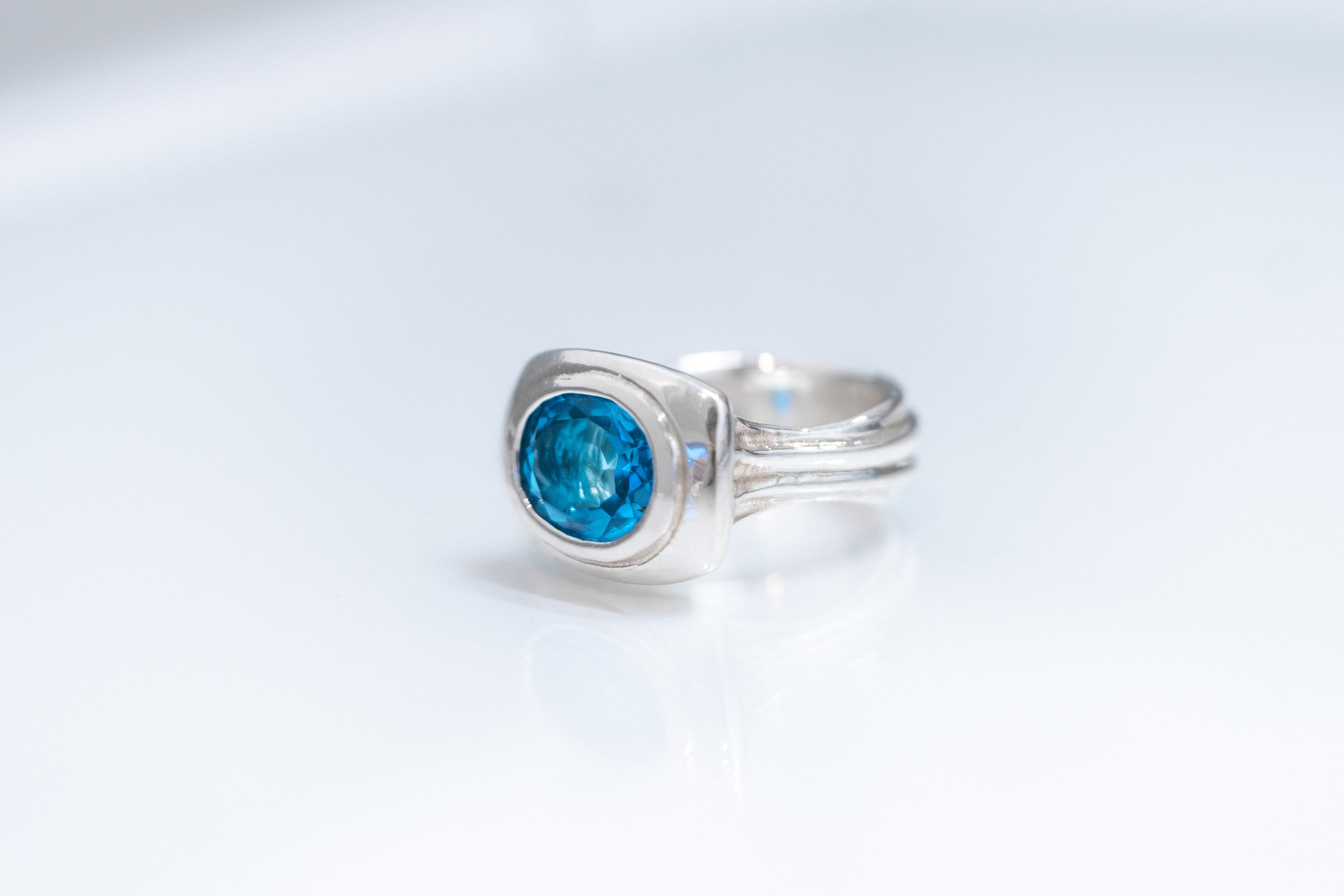 Oval Form sterling silver ring with east-west Swiss blue topaz bezel setting.